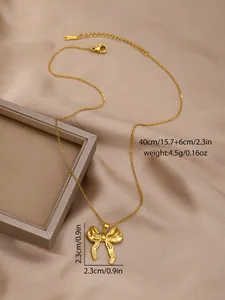 Detailed view of elegant gold bow pendant necklace on silk fabric background