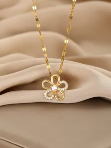 Macro view of gold flower pendant necklace with white crystals on champagne silk background