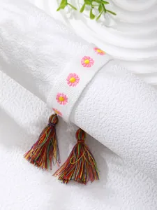 Detail of hand-woven bracelet featuring pink flower embroidery and colorful tassel charms