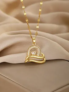 Macro detail of gold heart pendant necklace featuring pavé rhinestones and heart gemstone