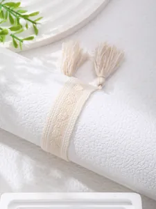 Macro shot of minimalist cream woven bracelet with tassels and diamond texture