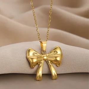 Elegant gold bow pendant necklace with polished mirror finish on silk background