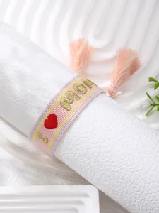 Detailed view of pink woven bracelet with gold MOM embroidery and decorative tassel