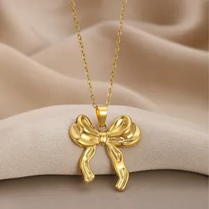 Elegant gold necklace with a polished bow-shaped pendant on silk fabric background