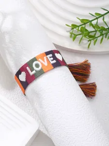 Close-up of woven bohemian bracelet featuring white embroidered LOVE text and colorful tassels