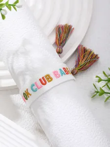 Detail of embroidered Book Club Babe white woven bracelet with colorful tassels