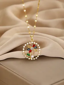 Macro shot of gold pendant featuring colorful floral gemstones and a white pearl detail
