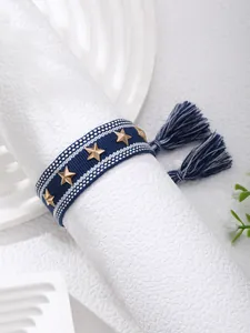Close-up of woven navy bracelet with gold star studs and fringe tassel details