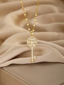 Close-up of golden key pendant with shimmering crystals on silk fabric