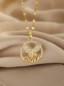 Macro shot of gold butterfly necklace pendant with love script and sparkling zircon stones
