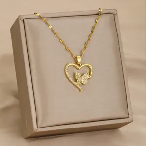 Golden heart pendant necklace with butterfly design and crystals on satin background
