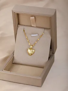 Primer plano de collar con colgante de corazón dorado acolchado en estuche de lujo