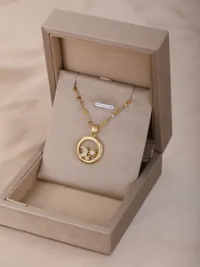 Detalle del colgante dorado con motivos de sol luna y estrellas sobre seda suave