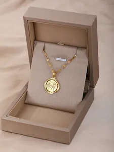 Detalle del colgante dorado con huellas de bebé y palabras de bendición grabadas