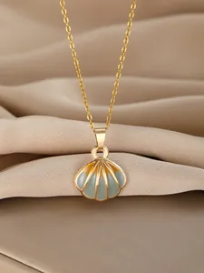 Detailed view of a gold shell pendant necklace with teal enamel on beige silk