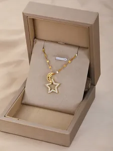 Detalle del collar dorado de luna y estrella con circonitas en una caja de regalo marrón