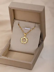 Detalle de collar con colgante de corona dorada y corazones de circón en estuche