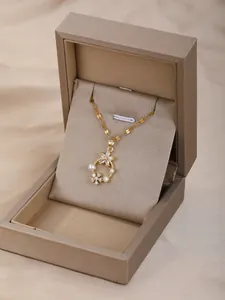 Detalle de colgante floral dorado con perlas y cristales en caja de joyería de lujo