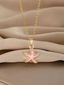 Macro shot of elegant starfish pendant with pink enamel and gold chain detail
