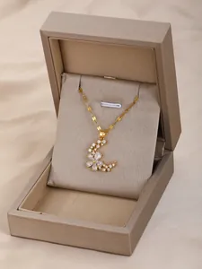 Detalle del colgante de flor lunar dorada con circonitas blancas en caja de joyería