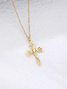 Detail of a hollowed rose flower cross pendant on a gold thin cable chain necklace