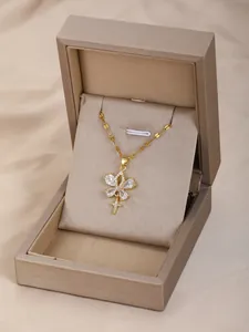 Detalle del collar dorado con colgante de circón y cruz sobre tela de satén