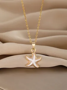 Macro shot of gold starfish pendant with white enamel inlay on champagne satin cloth