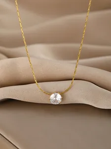 Close-up of golden necklace with a brilliant round-cut zircon stone on silk fabric