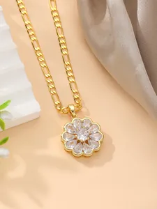 Detalle del collar con colgante de flor dorada, circonitas claras y cadena tipo Figaro