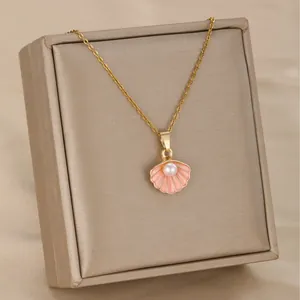 Golden scallop seashell necklace with pink enamel and pearl on satin background