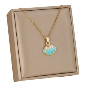Elegant gold shell pendant necklace with blue enamel on a champagne display cushion
