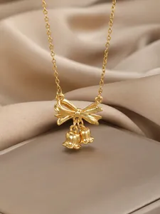 Detailed close-up of a gold bow pendant necklace with two delicate small bell charms