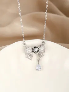 Macro detail of silver bow pendant with zircon, white pearl, and pear-cut crystal