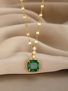 Macro shot of gold necklace with emerald square pendant and diamond accents on silk fabric