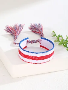 Detalle de pulsera trenzada de la amistad roja blanca azul con borlas en un soporte