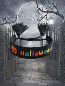 Detalle de pulsera negra de Halloween con bordado de calabaza naranja y borlas negras