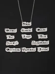 Macro shot of silver zodiac name necklaces in Gothic font on a black background