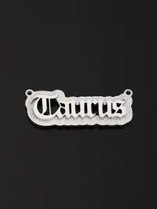 Macro view of silver stainless steel Taurus pendant with gothic lettering on black background