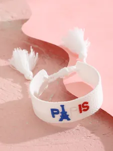 Detalle de pulsera trenzada blanca con bordado colorido de la Torre Eiffel de París y borlas