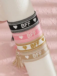 Detalle de cuatro pulseras de la amistad tejidas con texto BFF y adornos de borlas