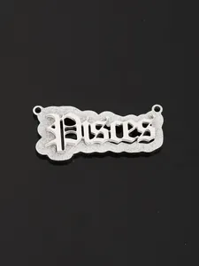 Macro shot of silver-toned Pisces zodiac pendant with gothic lettering on black background