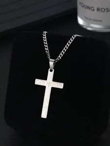 Macro detail of silver stainless steel cross pendant featuring engraved Lord's Prayer text