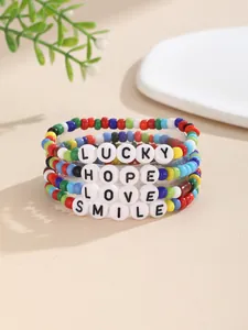 Detail von vier bunten Perlenarmbändern mit Lucky, Hope, Love und Smile Schriftzügen