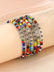 Detalle de pulseras de cuentas coloridas con dijes de letras en un soporte de exhibición