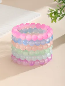 Detalle de seis pulseras de cuentas de vidrio esmerilado de colores en soporte