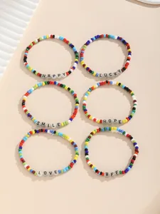 Primer plano de seis pulseras de la amistad con cuentas de colores y palabras positivas