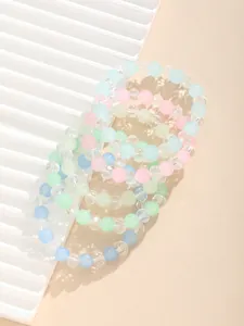 Detalle de cuentas mate macaron y dijes facetados en pulseras elásticas de varias capas