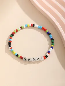 Primer plano de pulsera de cuentas coloridas con letras HAPPY sobre fondo amarillo