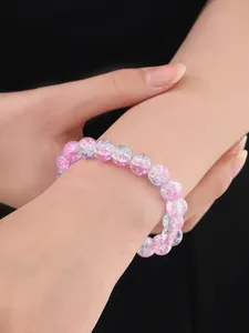 Primer plano de una pulsera de cuentas rosas con cristales craquelados en una muñeca