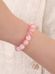 Primer plano de pulsera de cuentas rosa con textura agrietada en la muñeca de una mujer